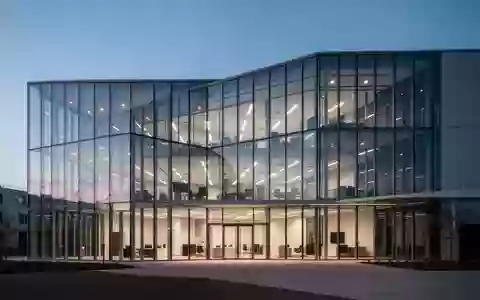 Moderne Büroarchitektur mit Glasfassade bei Dämmerung, symbolisiert betriebliche Investitionen und Unternehmensverwaltung. - Foto: über boerse-global.de