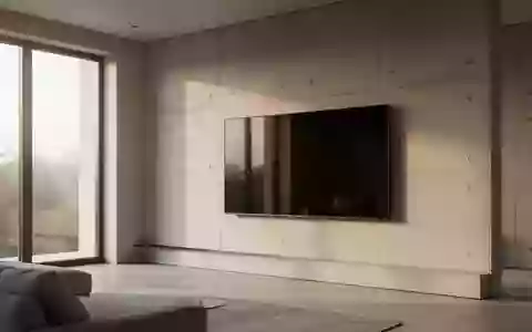 Ein minimalistisch eingerichtetes Wohnzimmer mit einem an einer Betonwand montierten, ausgeschalteten Fernsehbildschirm. - Foto: ĂĽber boerse-global.de