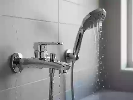 Ein glänzender Wasserhahn und ein Duschkopf in einem modernen Badezimmer bei natürlichem Tageslicht. - Foto: über boerse-global.de