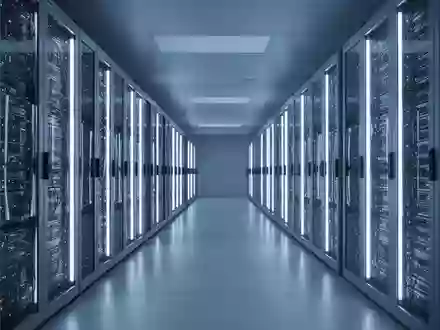 Ein langer, modern beleuchteter Korridor in einem Rechenzentrum mit leuchtenden Server-Racks in kühlem Blau. - Foto: über boerse-global.de