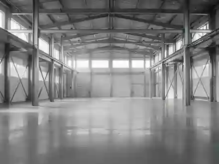 Helle, leere Industriehalle mit poliertem Betonboden und Stahlträgern in einer minimalistischen Architektur. - Foto: über boerse-global.de