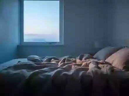 Ein minimalistisches Schlafzimmer bei Morgendämmerung mit einfallendem Tageslicht auf einem ungemachten Bett. - Foto: über boerse-global.de