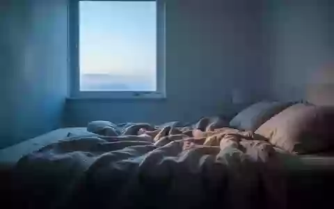 Ein minimalistisches Schlafzimmer bei Morgendämmerung mit einfallendem Tageslicht auf einem ungemachten Bett. - Foto: über boerse-global.de