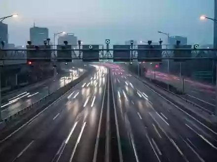 Eine moderne, mehrspurige Schnellstraße bei Dämmerung mit klarer Fahrbahnmarkierung und Sensortechnik an einer Brücke. - Foto: über boerse-global.de
