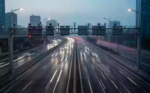 Eine moderne, mehrspurige Schnellstraße bei Dämmerung mit klarer Fahrbahnmarkierung und Sensortechnik an einer Brücke. - Foto: über boerse-global.de