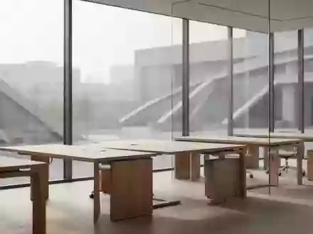 Ein minimalistisch gestalteter BĂĽroraum mit Holztischen und einfallendem Tageslicht vor einem urbanen Hintergrund. - Foto: ĂĽber boerse-global.de
