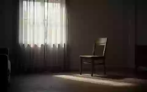 Ein einsamer, leerer Stuhl in einem ruhig beleuchteten Wohnzimmer am Fenster, der eine Atmosphäre der Isolation vermittelt. - Foto: über boerse-global.de