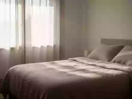 Ein minimalistisch eingerichtetes Schlafzimmer am frĂŒhen Morgen mit einfallendem Tageslicht auf einem bezogenen Bett. - Foto: ĂŒber boerse-global.de