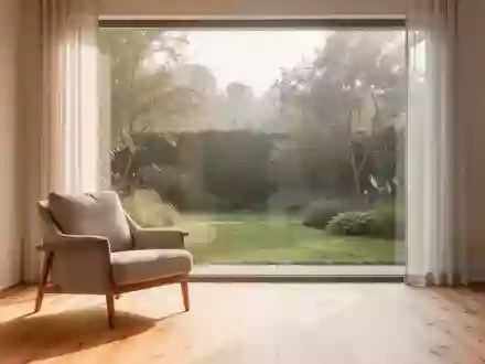 Ein helles, modern eingerichtetes Wohnzimmer mit einem bequemen Sessel und einem großen Fenster mit Blick in einen Garten. - Foto: über boerse-global.de