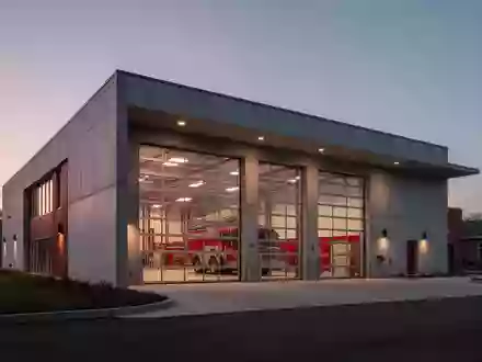 Modernes Feuerwehrgebäude in der Dämmerung mit minimalistischer Betonarchitektur und Glasfronten - Foto: über boerse-global.de