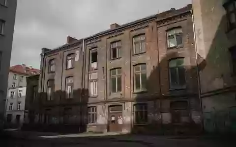 Fassade eines alten Backsteingebäudes in Berlin unter einem bewölkten Himmel, das leer und verlassen wirkt. - Foto: über boerse-global.de