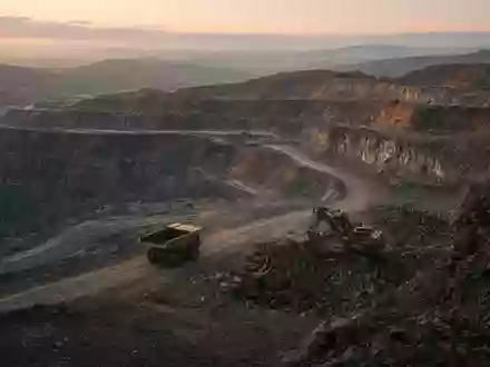 Ein moderner Tagebau bei Sonnenaufgang mit schwerem Gerät in einer weitläufigen Erdenlandschaft. - Foto: über boerse-global.de