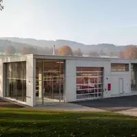 Modernes Feuerwehrgerätehaus aus Beton und Glas in einer ländlichen Umgebung bei Tageslicht. - Foto: über boerse-global.de