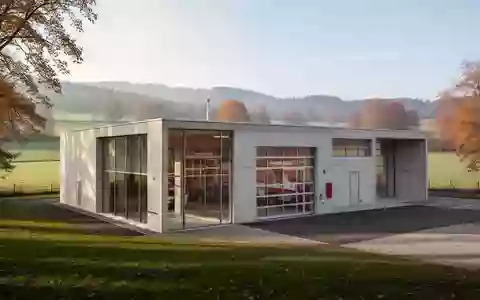 Modernes Feuerwehrgerätehaus aus Beton und Glas in einer ländlichen Umgebung bei Tageslicht. - Foto: über boerse-global.de