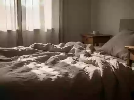 Ein lichtdurchflutetes Schlafzimmer am Nachmittag mit weichem Tageslicht, das sanfte Schatten auf ein ungemachtes Bett wirft. - Foto: über boerse-global.de