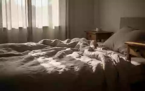 Ein lichtdurchflutetes Schlafzimmer am Nachmittag mit weichem Tageslicht, das sanfte Schatten auf ein ungemachtes Bett wirft. - Foto: über boerse-global.de