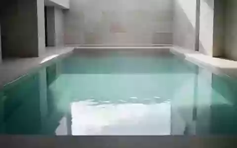 Ein ruhiges, leeres Schwimmbecken mit klarem Wasser und sanftem Lichteinfall in einer minimalistischen Architektur. - Foto: über boerse-global.de