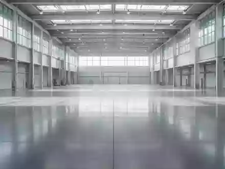 Eine weitläufige, leere Industriehalle mit poliertem Betonboden und minimalistischer Architektur bei natürlichem Lichteinfall. - Foto: über boerse-global.de