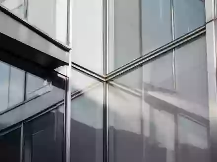 Moderne architektonische Fassade aus Glas und Stahl mit Fokus auf geometrische Linien und Lichtreflexionen. - Foto: über boerse-global.de