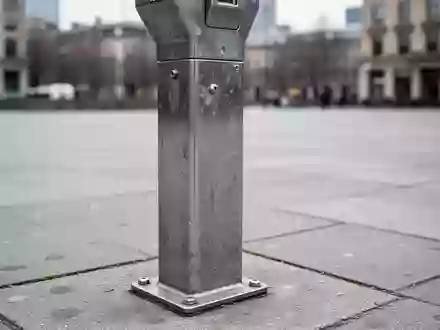 Ein einsamer Parkscheinautomat auf einem grauen Gehweg bei bewölktem Tageslicht. - Foto: über boerse-global.de