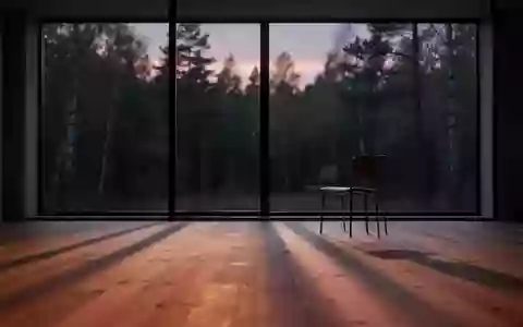 Ein minimalistischer, ruhiger Raum bei Dämmerung mit langen Schatten und Blick auf einen Wald durch ein großes Fenster. - Foto: über boerse-global.de