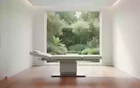 Ein minimalistischer, heller medizinischer Untersuchungsraum mit weichem Tageslicht und Blick in einen grünen Garten. - Foto: über boerse-global.de