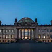 Die beleuchtete Reichstagskuppel in Berlin bei Dämmerung vor einem tiefblauen Abendhimmel. - Foto: über boerse-global.de