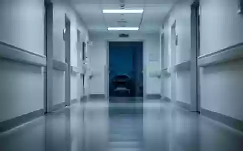 Ein leerer, steriler Krankenhausflur in kühlem, klinischem Licht mit polierten Böden und weißen Wänden. - Foto: über boerse-global.de