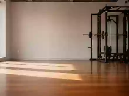 Ein minimalistisch gestalteter, lichtdurchfluteter Fitnessraum mit leerer Trainingsfläche und einer leeren Hantelablage. - Foto: über boerse-global.de