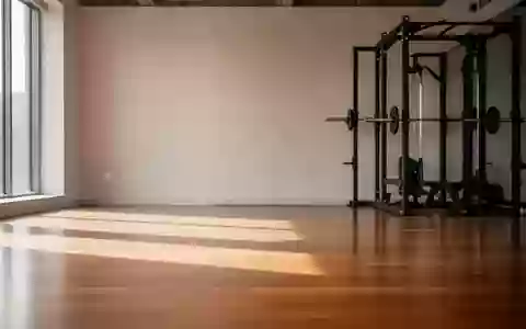 Ein minimalistisch gestalteter, lichtdurchfluteter Fitnessraum mit leerer Trainingsfläche und einer leeren Hantelablage. - Foto: über boerse-global.de