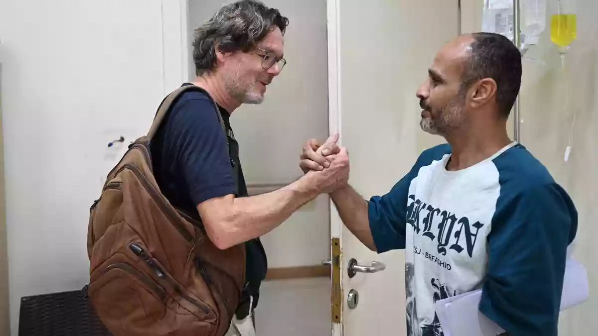 Oliver Mohr (l), ehrenamtlicher Arzt bei Malteser International und Ahmeds Vater Ejad al-Chair (r), verabschieden sich.  - Bild: Michael Brandt/dpa