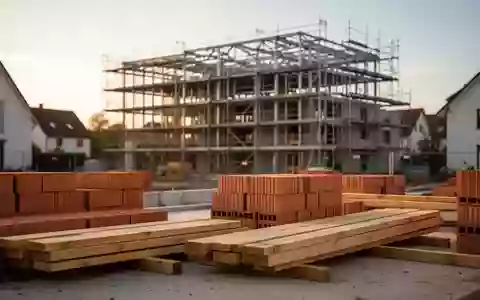 Eine Baustelle mit gestapelten Ziegeln und einem Rohbau für ein Mehrfamilienhaus bei Sonnenuntergang. - Foto: über boerse-global.de