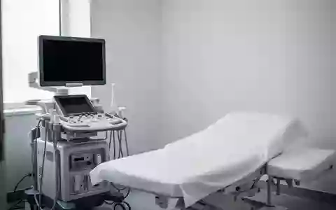Ein klinischer Untersuchungsraum mit einem modernen Ultraschallgerät und einer leeren Untersuchungsliege in hellem, natürlichem Licht. - Foto: über boerse-global.de