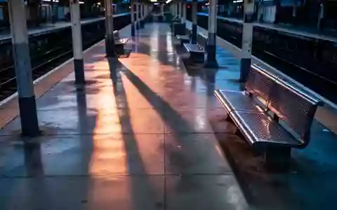 Ein leerer, ruhig beleuchteter Bahnsteig in der Abenddämmerung mit langen Schatten und schlichten Sitzgelegenheiten. - Foto: über boerse-global.de