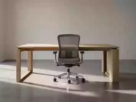 Ein minimalistischer, leerer Arbeitsbereich mit einem Holztisch und einem ergonomischen Stuhl in natürlichem Licht. - Foto: über boerse-global.de