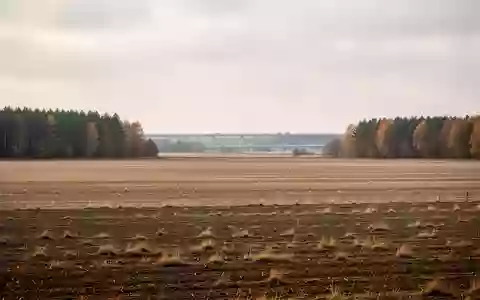 Weite, unberührte Ackerflächen im Mühlenbecker Land unter einem bewölkten Himmel, im Hintergrund schemenhaft eine Autobahntrasse. - Foto: über boerse-global.de