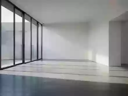 Ein minimalistischer, lichtdurchfluteter Raum mit klaren architektonischen Linien und Schattenwurf auf Betonboden. - Foto: über boerse-global.de