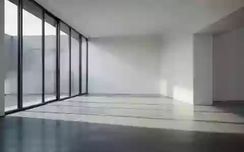 Ein minimalistischer, lichtdurchfluteter Raum mit klaren architektonischen Linien und Schattenwurf auf Betonboden. - Foto: über boerse-global.de