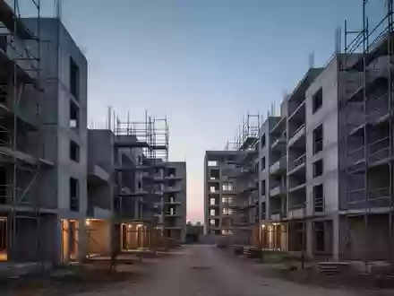 Unfertige Wohngebäude im Rohbau auf einer Baustelle in der Abenddämmerung. - Foto: über boerse-global.de