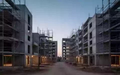 Unfertige Wohngebäude im Rohbau auf einer Baustelle in der Abenddämmerung. - Foto: über boerse-global.de