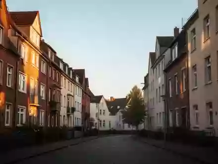 Eine ruhige Wohnstraße mit mehrstöckigen Wohngebäuden in einer deutschen Stadt bei spätem Nachmittagslicht. - Foto: über boerse-global.de