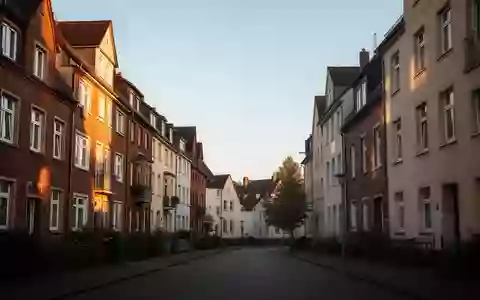 Eine ruhige Wohnstraße mit mehrstöckigen Wohngebäuden in einer deutschen Stadt bei spätem Nachmittagslicht. - Foto: über boerse-global.de