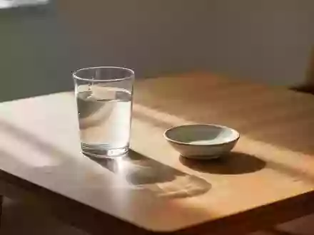 Ein minimalistischer Holztisch mit einem Glas Wasser in einem hellen, ruhigen Raum. - Foto: über boerse-global.de