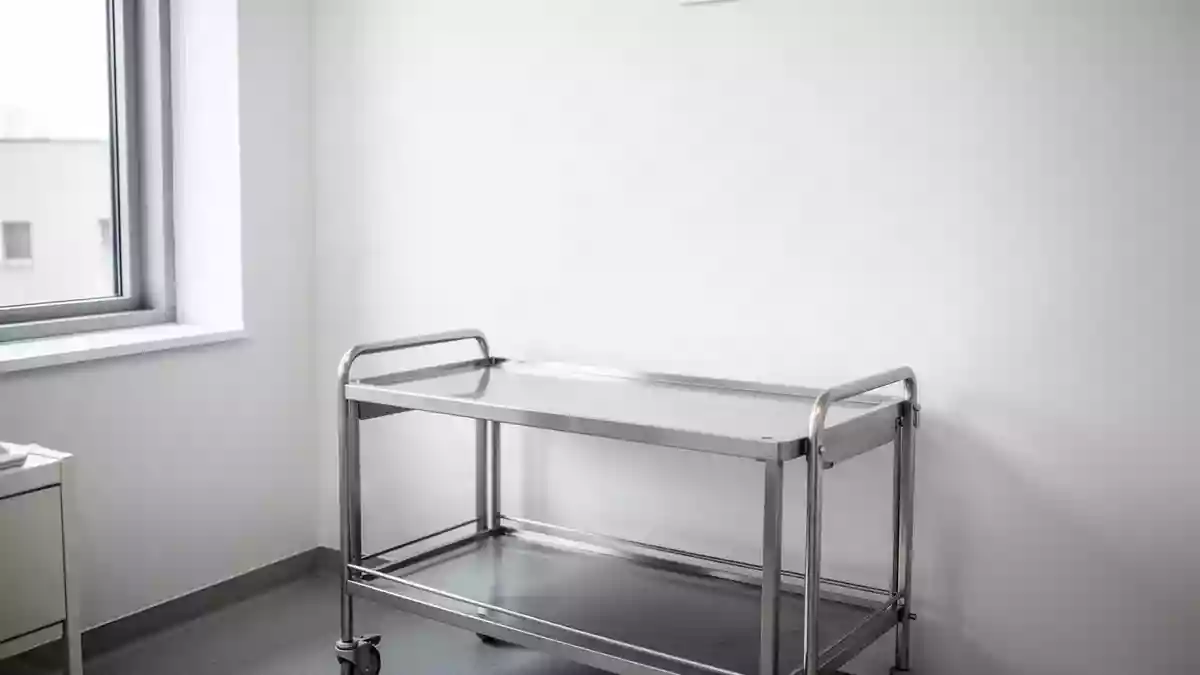Ein heller, minimalistischer Behandlungsraum in einer Arztpraxis mit einem leeren medizinischen Beistelltisch. Illustration mit AI erstellt.