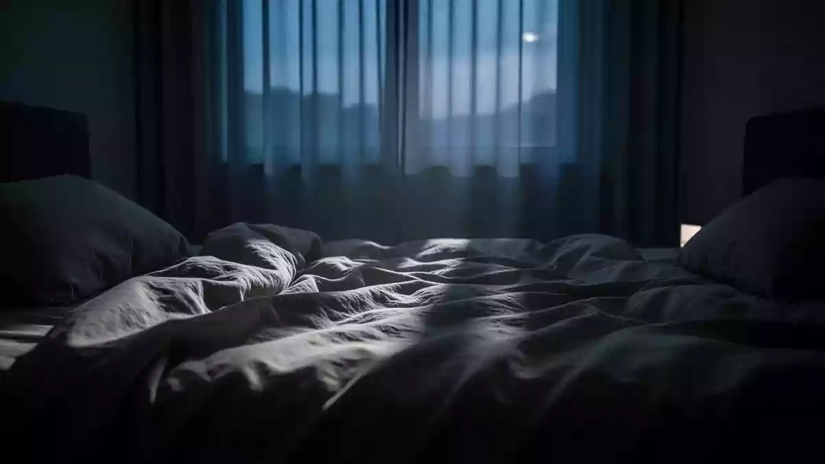 Ein ungemachtes Bett in einem abgedunkelten Schlafzimmer bei einsetzendem Tageslicht, das eine ruhige und melancholische Stimmung vermittelt. Illustration mit AI erstellt.