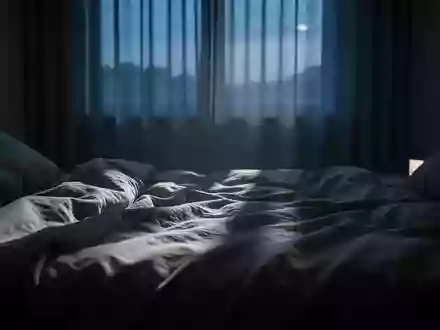 Ein ungemachtes Bett in einem abgedunkelten Schlafzimmer bei einsetzendem Tageslicht, das eine ruhige und melancholische Stimmung vermittelt. - Foto: über boerse-global.de