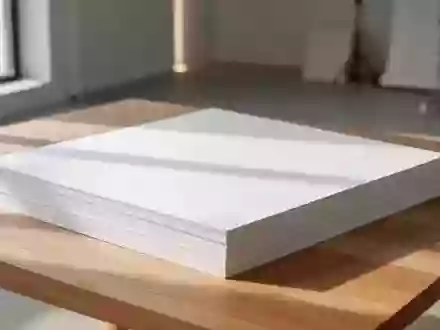 Stapel aus hochwertigem, dickem Kartonpapier auf einem hellen Holztisch in einem minimalistischen, lichtdurchfluteten Raum. - Foto: über boerse-global.de