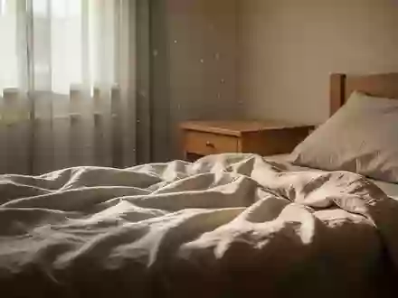 Ein sonnendurchflutetes, ruhiges Schlafzimmer mit einem ungemachten Bett und einem schlichten Nachttisch in natürlichem Licht. - Foto: über boerse-global.de