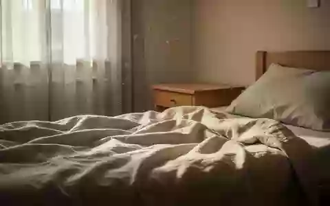 Ein sonnendurchflutetes, ruhiges Schlafzimmer mit einem ungemachten Bett und einem schlichten Nachttisch in natürlichem Licht. - Foto: über boerse-global.de