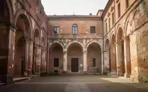 Ein sonnendurchfluteter, historischer Innenhof mit alten Backsteinmauern und Rundbögen in Piacenza. - Foto: über boerse-global.de